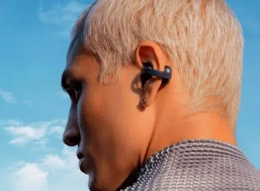 Persona de perfil con auriculares de clip en la oreja y cielo azul de fondo.