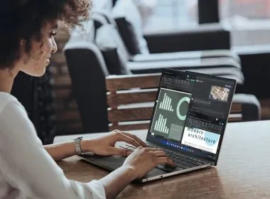 Mujer trabajando en un ordenador portátil Lenovo ThinkPad con varias ventanas abiertas en pantalla que muestran gráficos y documentos.