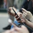 Primer plano de varias personas sentadas utilizando sus teléfonos móviles en un espacio público.