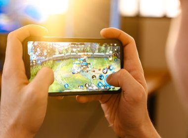 Chico caucásico jugando videojuegos en su teléfono móvil en casa