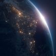 Vista del amanecer sobre la curvatura de la Tierra desde el espacio con las luces nocturnas de las ciudades encendidas.