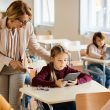 La colegiala utiliza el panel táctil con la ayuda del profesor durante una clase en el aula.