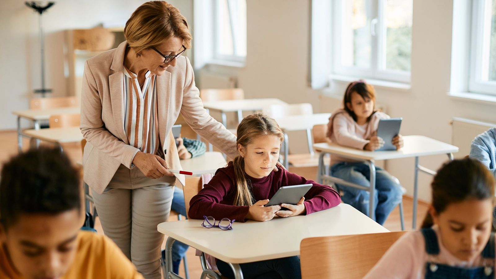 La colegiala utiliza el panel táctil con la ayuda del profesor durante una clase en el aula.