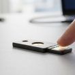 Dedo pulsando el sensor de una llave de seguridad física sobre una mesa.