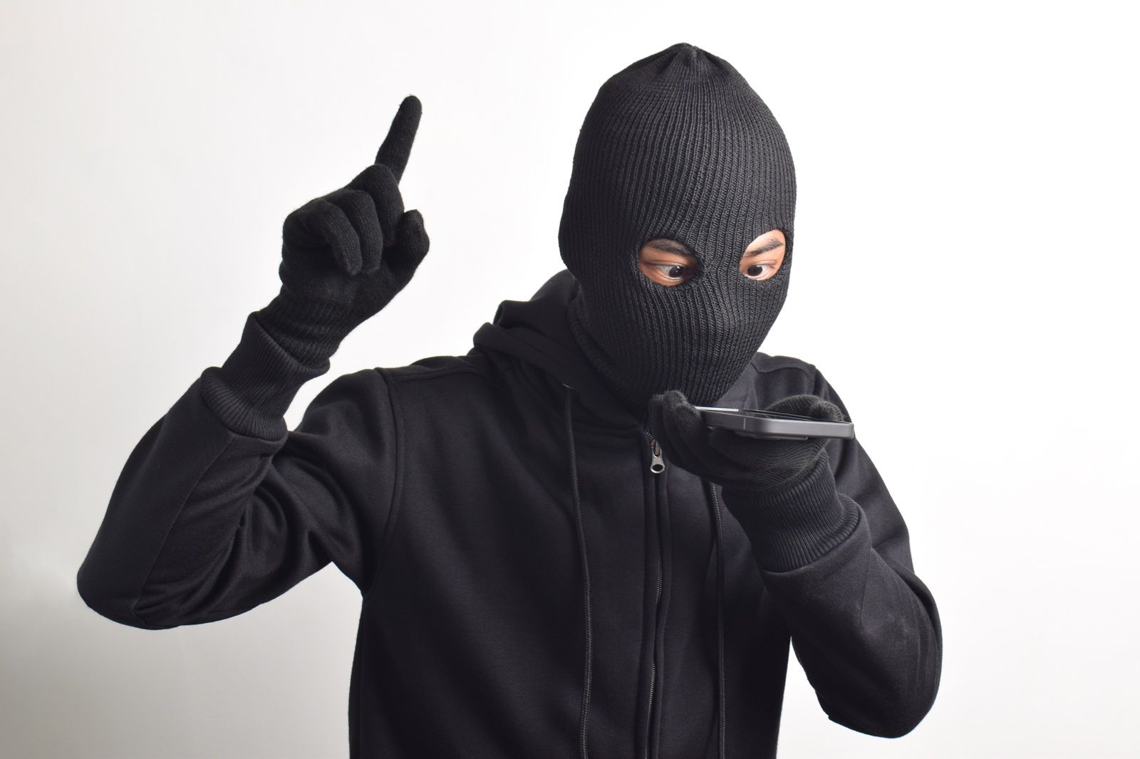 Hombre misterioso con capucha negra y máscara extorsionando dinero en una llamada