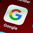 Primer plano de la aplicación de búsqueda de Google instalada en un teléfono móvil junto a otros iconos de redes sociales.