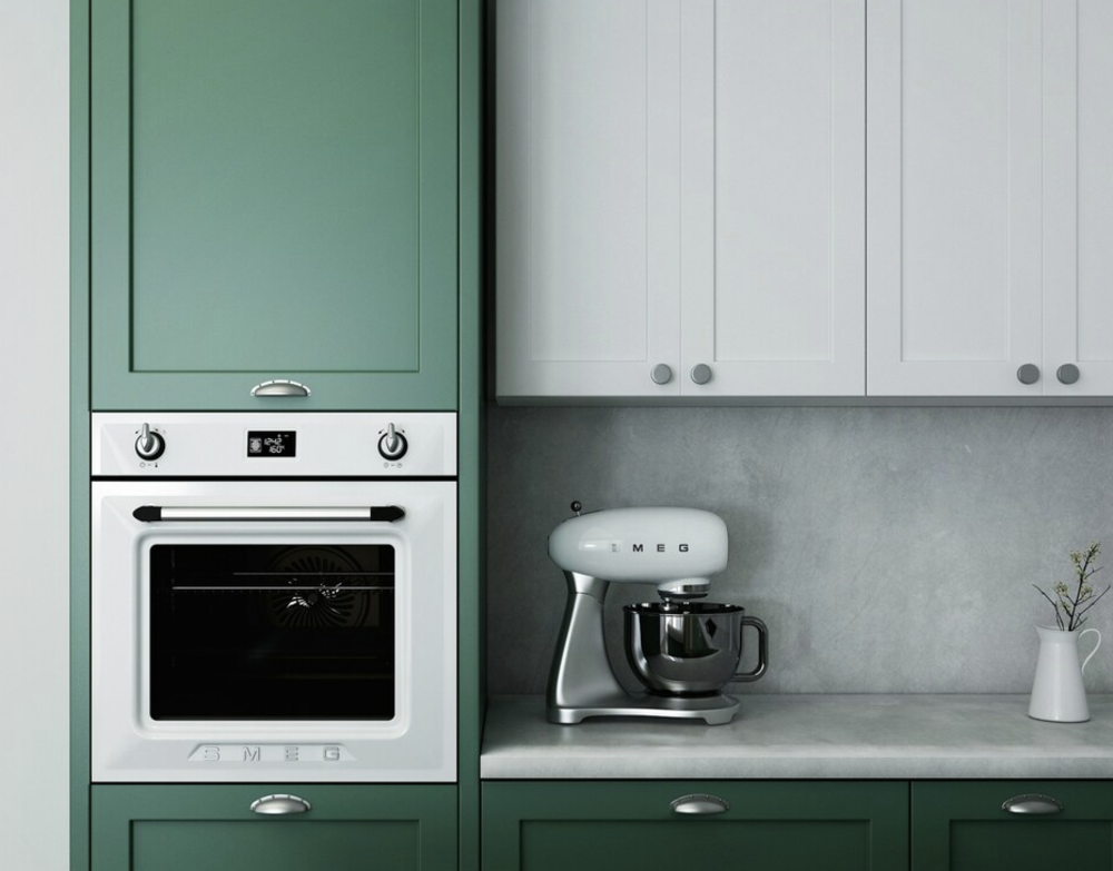 Horno encastrado de color blanco y robot de cocina sobre encimera en una cocina con armarios verdes y blancos.