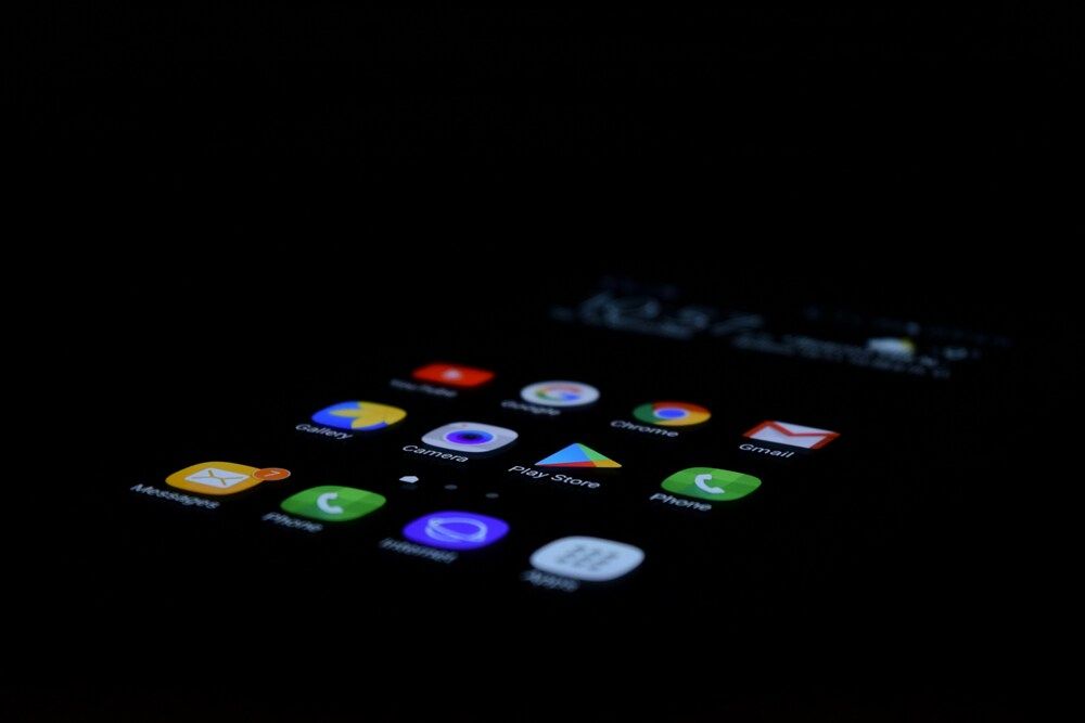Primer plano de la pantalla de un teléfono Android con iconos de aplicaciones iluminados sobre fondo oscuro.