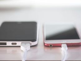 Dos teléfonos inteligentes conectados a cables de carga sobre una superficie clara.