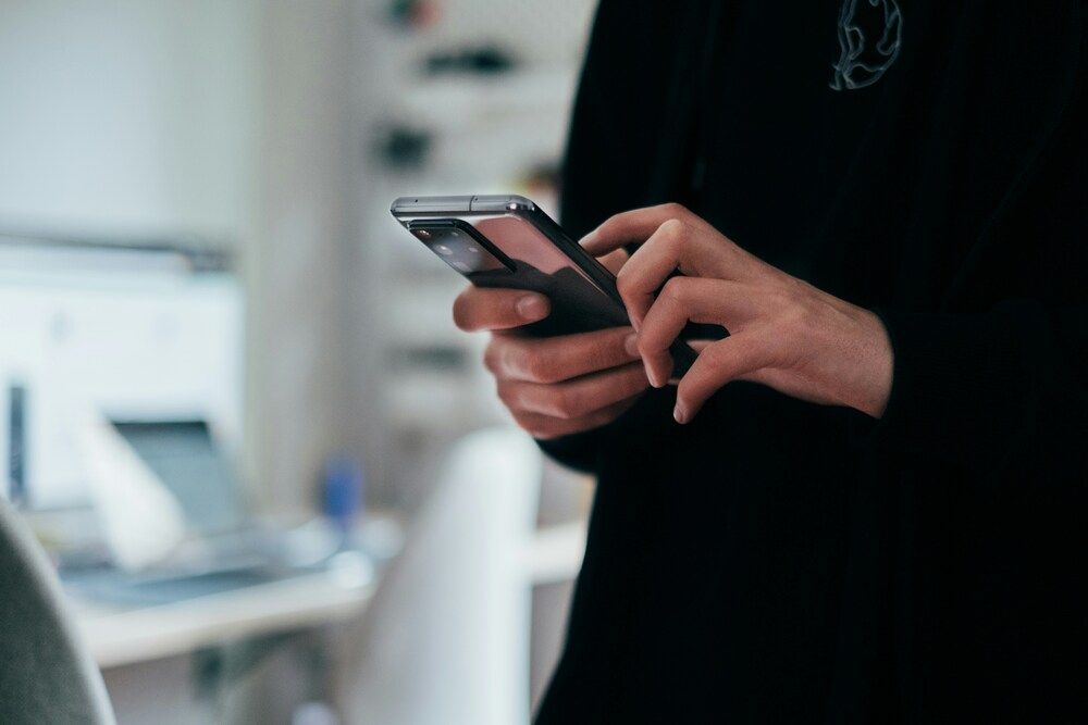 Primer plano de manos sujetando un smartphone con un módulo de cámaras trasero prominente.