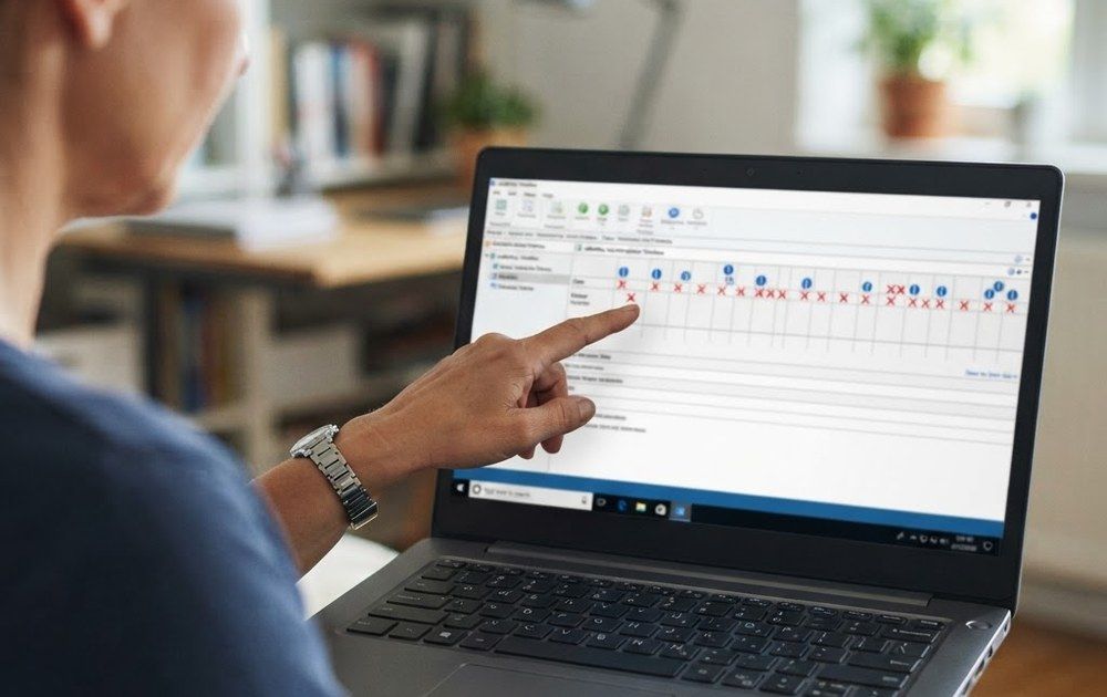 Persona señalando el historial de fiabilidad del sistema en la pantalla de un ordenador portátil Lenovo.