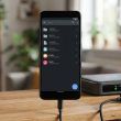 Teléfono inteligente conectado por cable junto a un servidor y un disco duro externo en un escritorio.