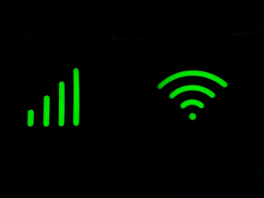 Iconos luminosos de cobertura y señal Wi-Fi en color verde sobre fondo oscuro.