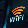 Pegatina con el símbolo de WiFi naranja y texto blanco sobre el cristal oscuro de un vehículo de transporte público.