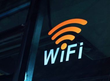 Pegatina con el símbolo de WiFi naranja y texto blanco sobre el cristal oscuro de un vehículo de transporte público.